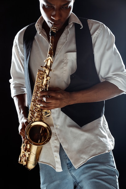 Musicien de jazz jouant du saxophone en studio sur un mur noir