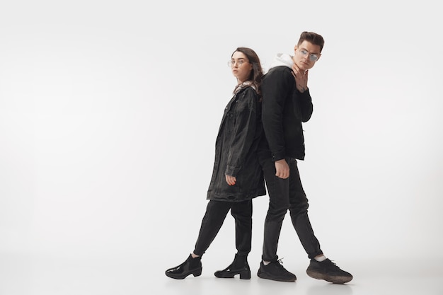 Photo gratuite en noir. couple à la mode à la mode isolé sur le mur du studio blanc.