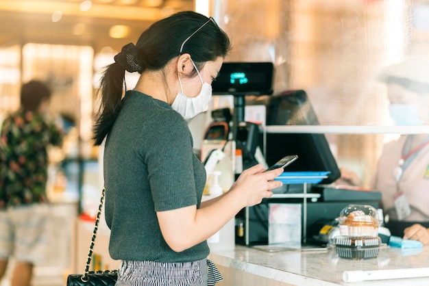 Photo gratuit nouvelle normalité après l'épidémie de covid progrès du paiement des femmes asiatiques acheter l'application de numérisation par smarthine nouveau mode de vie shopping sans numéraire et sans contact dans le comptoir de caisse du grand magasin