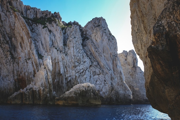 Photo gratuite océan entouré de falaises rocheuses scintillant sous le ciel bleu - idéal pour les papiers peints