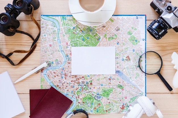 Photo gratuite papier blanc vierge; tasse à thé et divers accessoires de voyageur sur fond en bois