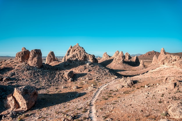 Photo gratuit paysage d'un désert avec route vide et falaises sous le ciel clair