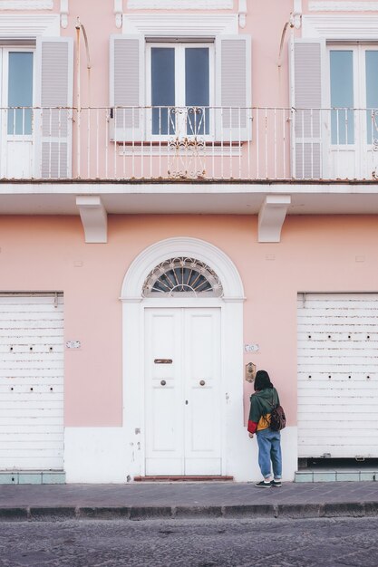 Photo gratuite personne debout devant le bâtiment peint en rose et blanc