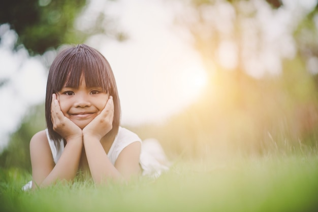 Photo gratuit petite fille allongée confortablement sur l&#39;herbe et souriant