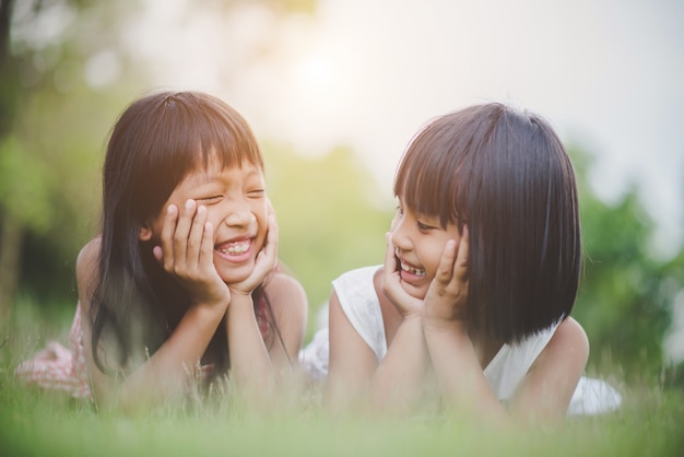 Photo gratuit petite fille avec un ami allongé confortablement sur l&#39;herbe et souriant