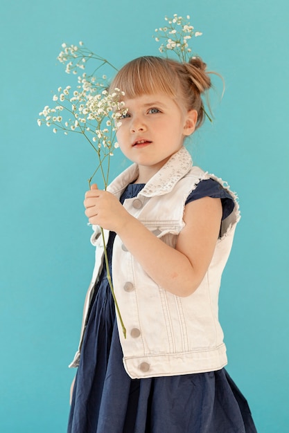 Photo gratuite petite fille posant avec des fleurs de printemps