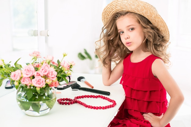 Photo gratuite une petite fille avec une robe rouge et des cosmétiques.