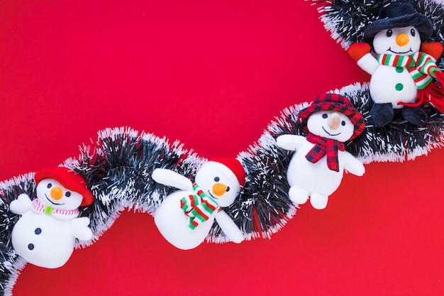 Petits bonhommes de neige sur des guirlandes sur une table rouge