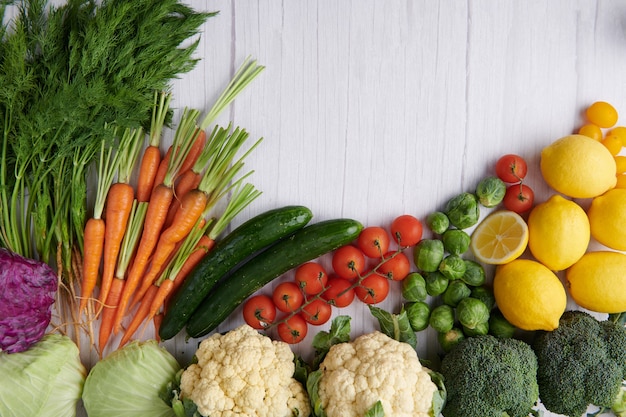 Photo gratuite photographie alimentaire différents fruits et légumes sur la surface de la table en bois blanc