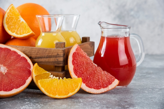 Photo gratuit pichets en verre de jus de pamplemousse avec des tranches de fruits orange.