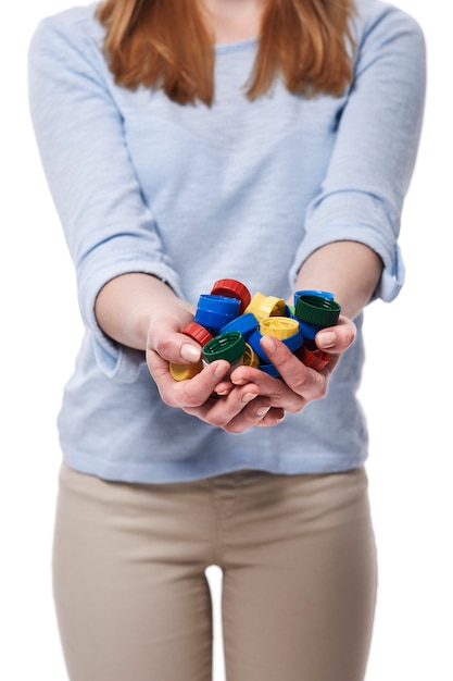 Pile de capsules de bouteilles dans les mains de la femme