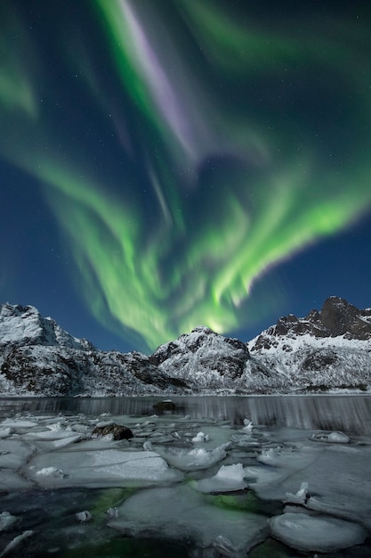 Photo gratuite un plan vertical de montagnes enneigées sous une belle lumière polaire la nuit