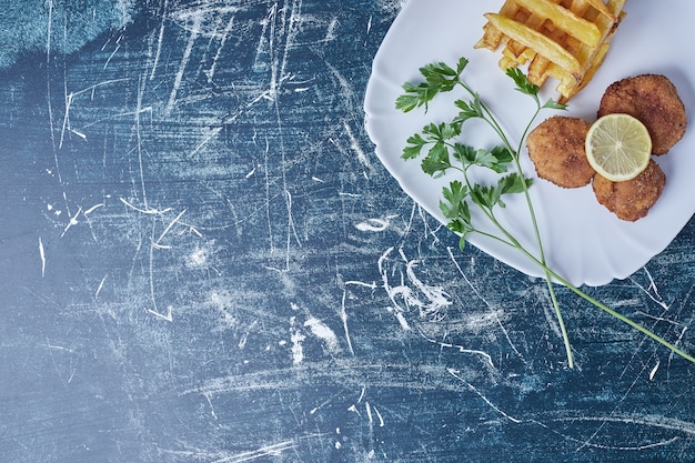 Photo gratuite pommes de terre sautées avec cotlets et citron.