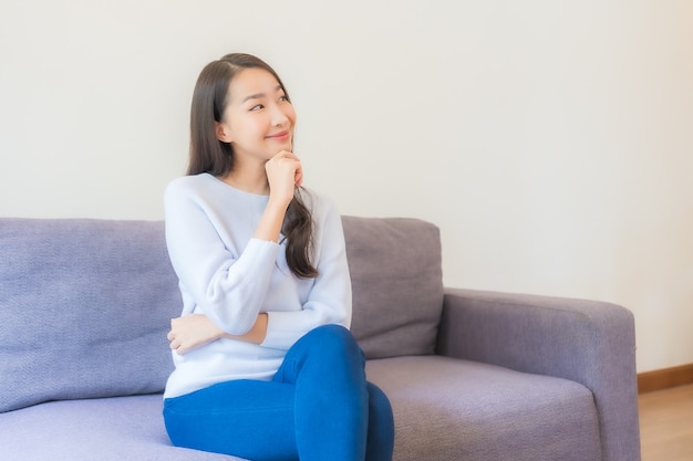 Photo gratuite portrait belle jeune femme asiatique se détendre sourire sur canapé dans le salon