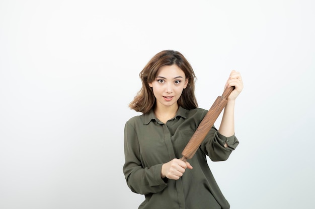 Portrait de belle jeune femme avec un rouleau à pâtisserie en bois debout. Photo de haute qualité