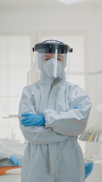 Photo gratuite portrait de dentiste debout en combinaison de protection contre les virus à la clinique buccale. femme caucasienne portant une combinaison ppe préparée pour une opération de dentisterie et une consultation chirurgicale