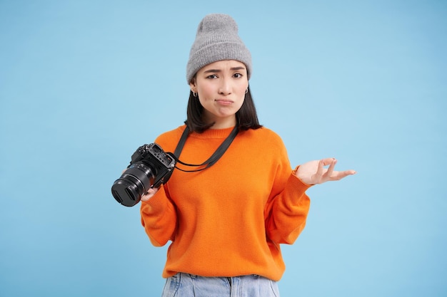 Photo gratuit portrait d'une femme asiatique au chapeau tenant un appareil photo numérique avec un photographe non professionnel au visage confus