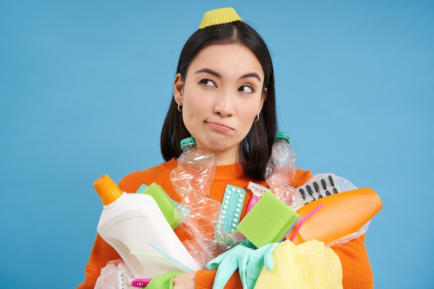 Photo gratuite portrait d'une femme asiatique avec des bouteilles en plastique vides regarde de côté avec un visage pensant recycler les ordures à