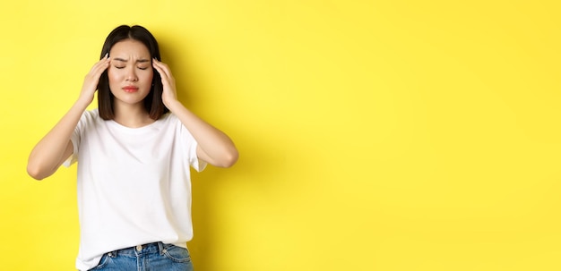 Photo gratuite portrait d'une femme asiatique fermer les yeux et froncer les sourcils de la migraine touchant la tête se sentant étourdi par les maux de tête