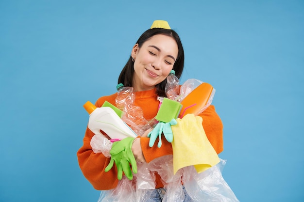 Photo gratuite portrait d'une femme asiatique souriante étreignant des bouteilles en plastique vides et des éco-activistes de déchets recyclables comme