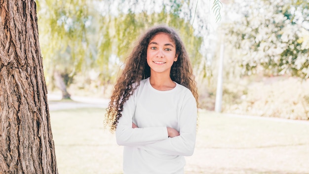 Photo gratuite portrait d'une fille heureuse avec bras croisés debout dans le jardin