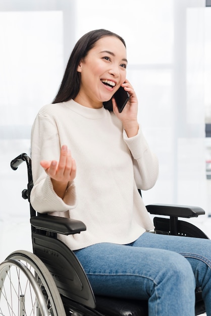 Photo gratuite portrait, de, a, handicapé, sourire, jeune femme, séance fauteuil chaise, parler, sur, téléphone portable, haussement épaules