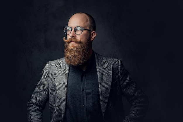 Photo gratuite portrait d'homme barbu rousse à lunettes vêtu d'un élégant costume de laine sur fond gris.