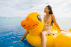 Photo gratuite portrait de jeune femme asiatique sur canard jaune gonflable flotteur autour de la piscine extérieure de l'hôtel