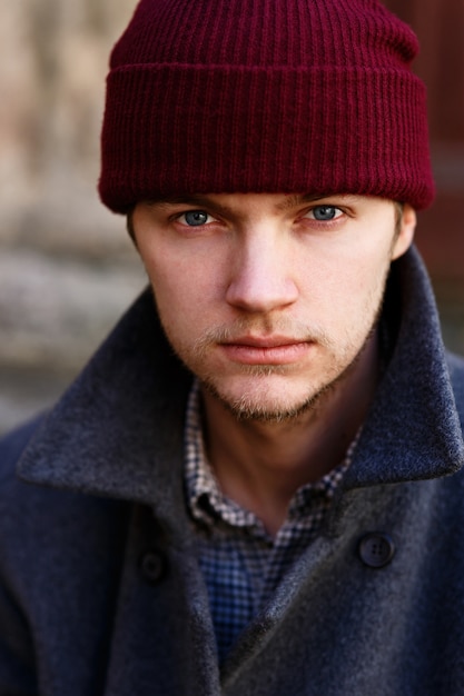 Photo gratuite portrait de jeune homme au chapeau rouge et manteau gris