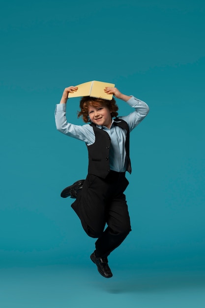 Photo gratuite portrait of young boy student in school uniform jumping mid-air