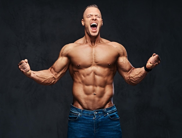 Photo gratuite portrait en studio d'un homme musclé torse nu dans un jean sur fond gris.