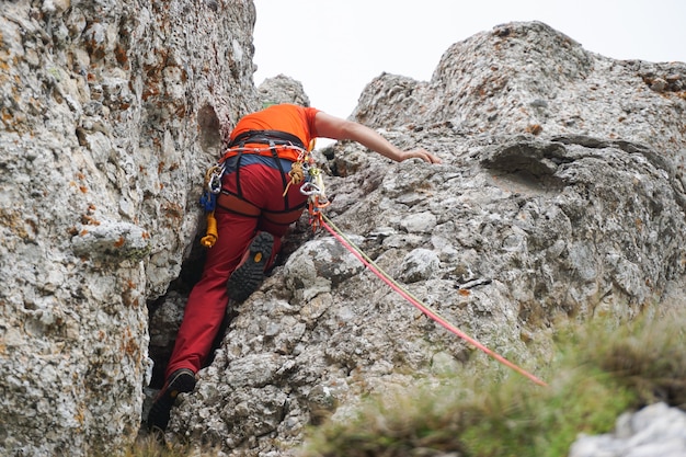 Photo gratuite prise de vue en contre-plongée d'un homme qui grimpe à la corde sur une falaise rocheuse