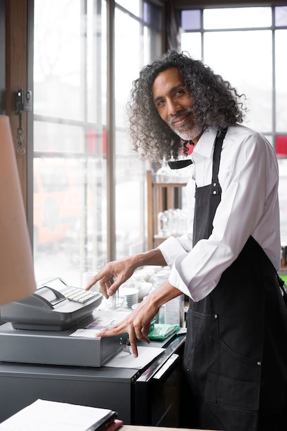 Photo gratuit propriétaire d'entreprise à coup moyen avec caisse enregistreuse