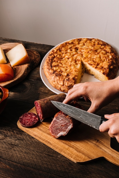 Recadrer les mains en tranchant des saucisses près d&#39;une tarte