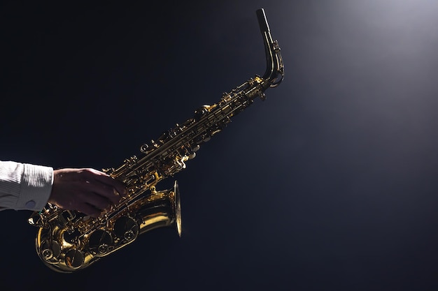 Photo gratuite saxophone entre les mains d'un homme sur un espace de copie de fond sombre