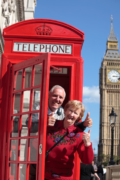 Photo gratuite senior couple en boîte téléphonique rouge avec big ben à londres