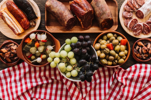 Serviette et raisins près de cornichons et de saucisses