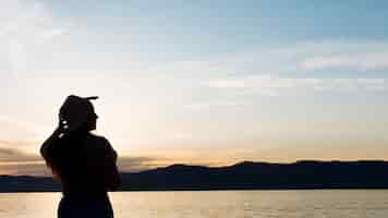 Photo gratuite silhouette femme au coucher du soleil avec des montagnes