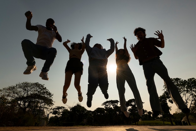 Photo gratuite silhouettes d'amis plein coup sautant au coucher du soleil