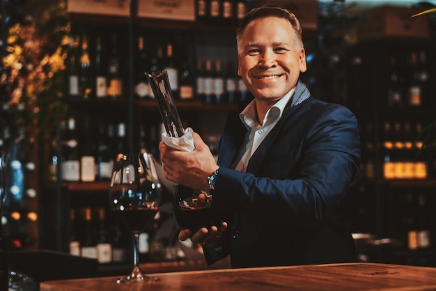 Photo gratuite un sommelier souriant et heureux est prêt à essayer un nouveau vin rouge dans une boutique de vins artisanaux.