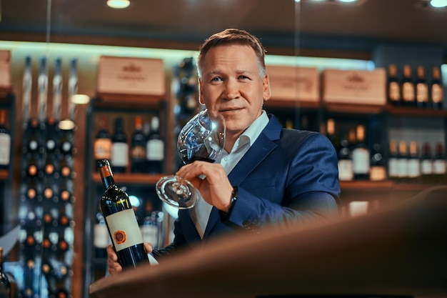 Photo gratuite un sommelier de vin élégant et pensif est prêt à essayer un nouveau vin rouge dans une boutique de vins artisanaux.