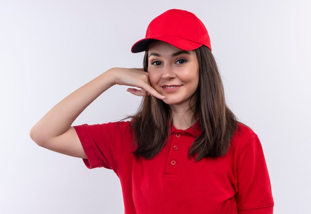 Photo gratuit souriante jeune femme de livraison portant un t-shirt rouge en bonnet rouge fait appel avec ses mains sur un mur blanc isolé