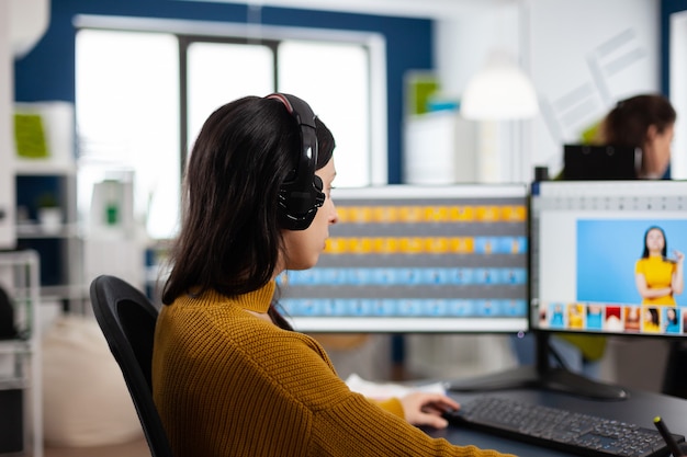 Photo gratuite spécialiste du retoucheur focalisé travaillant sur ordinateur dans un environnement de bureau créatif portant un casque