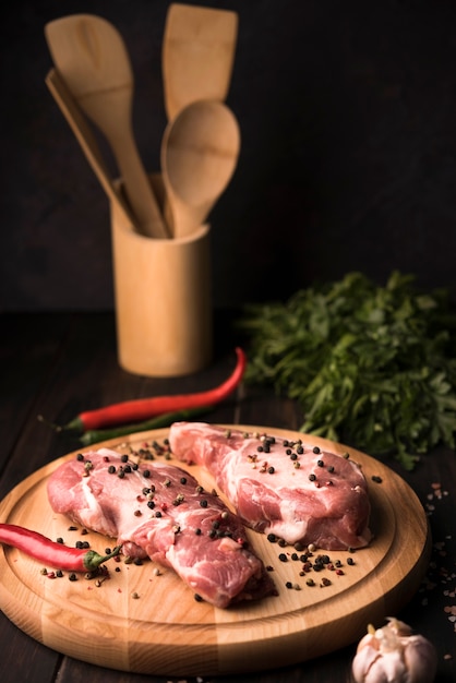 Photo gratuite steak d'angle élevé sur planche de bois avec du poivre