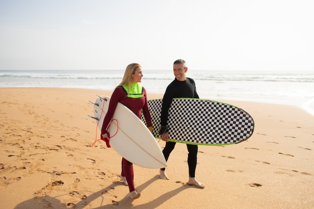 Photo gratuit surfeurs heureux s'éloignant de la plage et parler