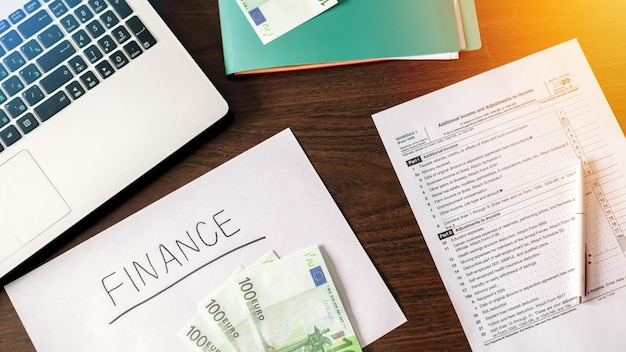 Table avec des trucs de travail des finances. Ordinateur portable, argent, stylo, papiers