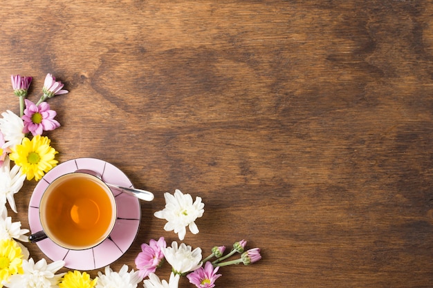 Tasse à thé aux herbes et belles fleurs au coin du fond en bois