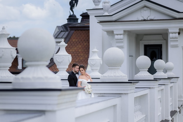 Photo gratuite tendre couple amoureux se tient à l'extérieur près du bâtiment le jour du mariage