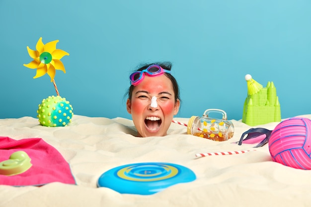 Photo gratuite tête de jeune femme avec crème solaire sur le visage entouré d'accessoires de plage