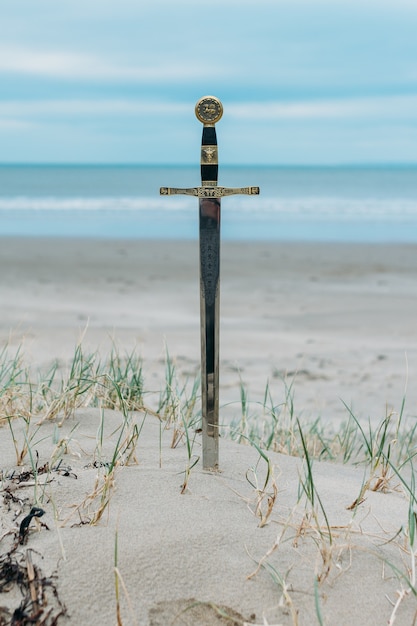 Photo gratuite tir vertical d'une épée dans la plage de sable